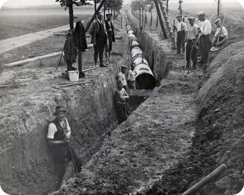 Historische Aufnahme von Arbeitern, die Rohrleitungen verlegen.